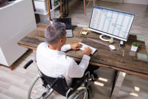 older man in wheelchair at desk